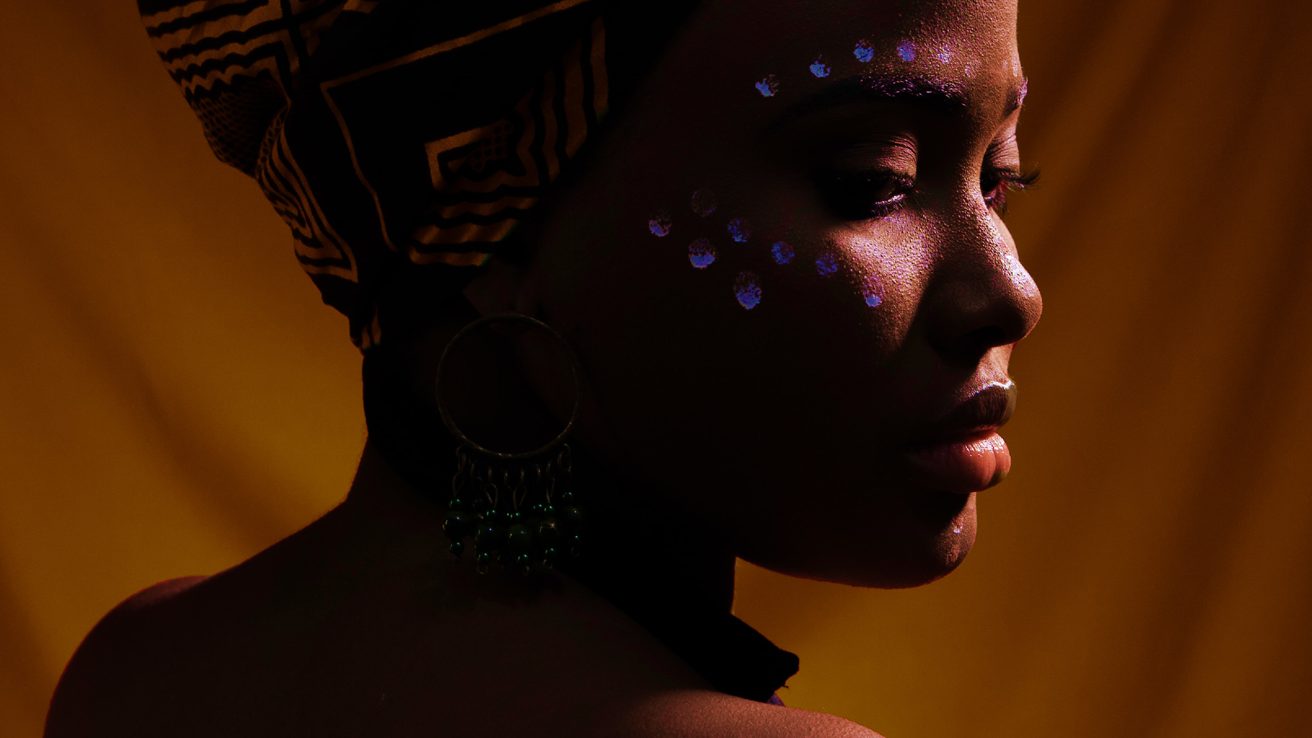 African American woman with glowing markings around her eyes. 