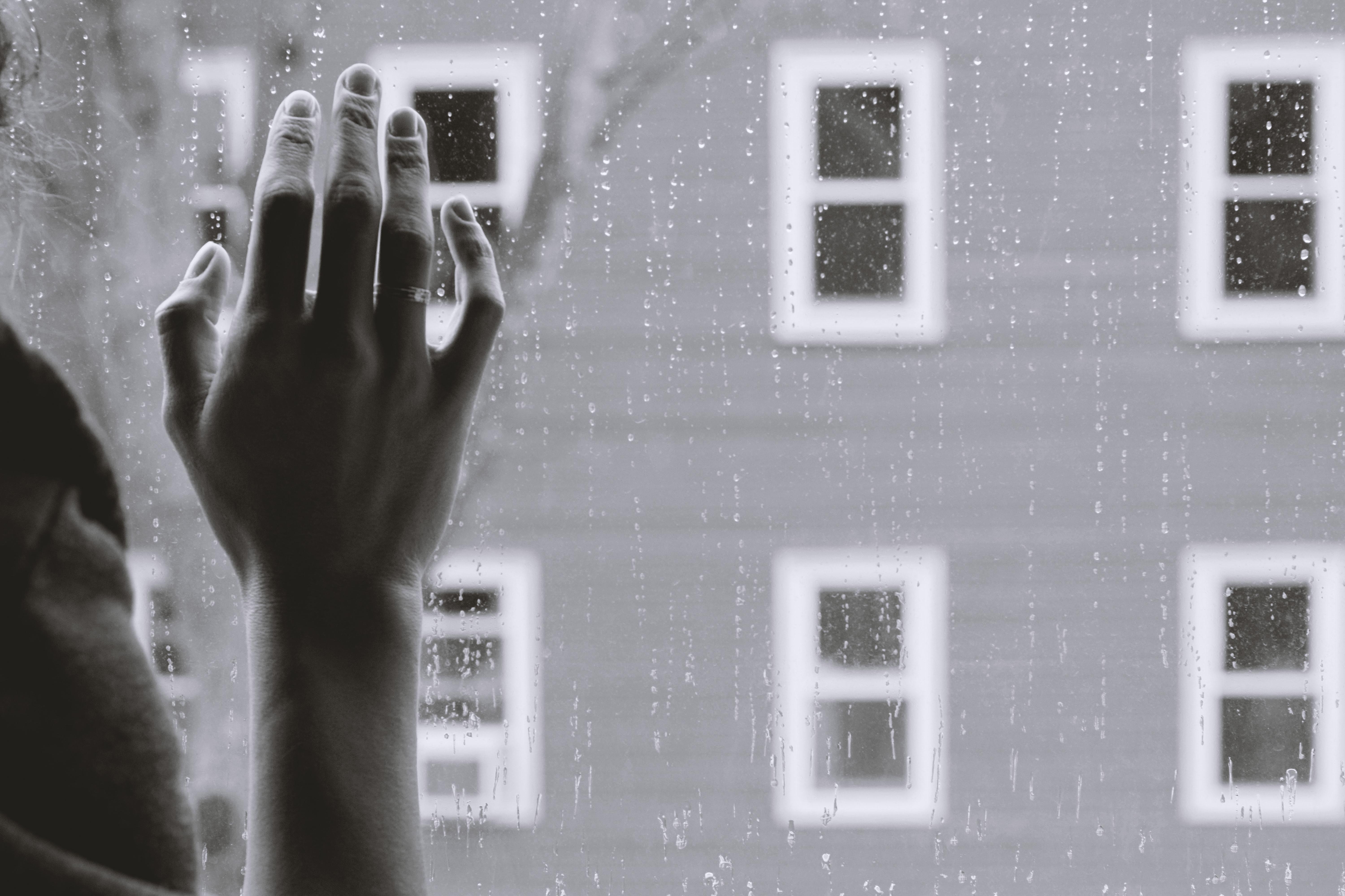 Black and white image of hand on window.