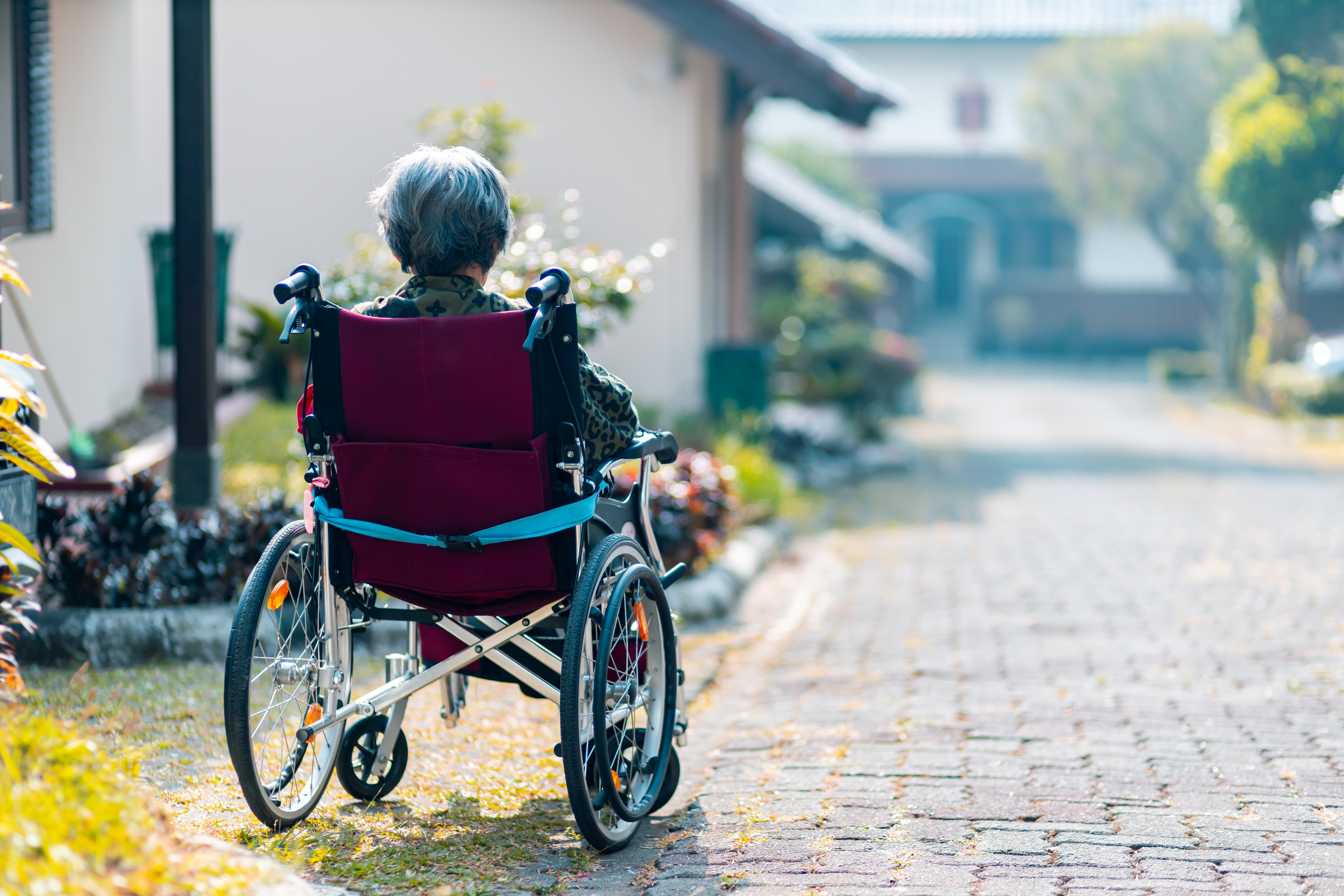 Senior in wheelchair outside, facing back