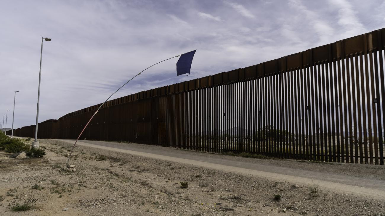 A blue flag marks the location of a nearby water station at the U.S.-Mexico border wall at the Organ Pipe Cactus Nation- al Monument.