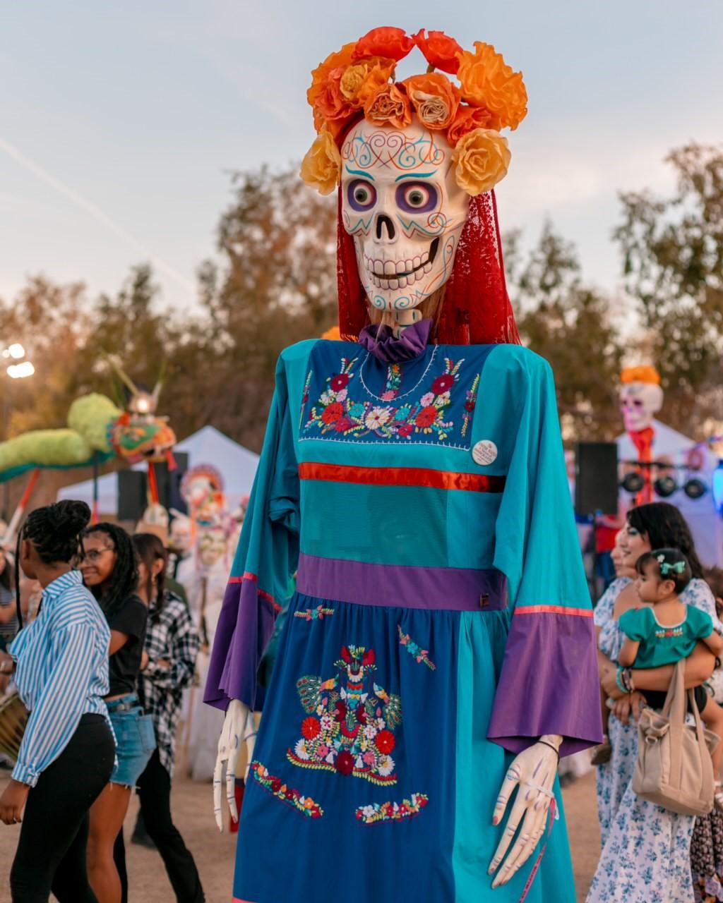 An adorned calavera is visible in a crowd during Day of the Dead festivities.